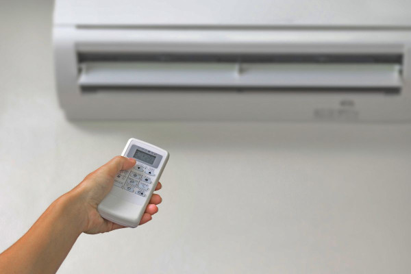 Woman turning off her split system air conditioner before disconnecting it.