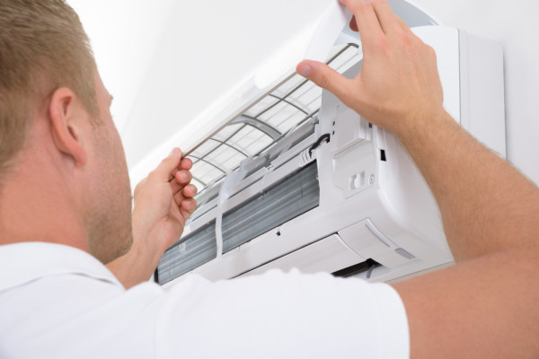 someone checking the air filters of an air conditioning system