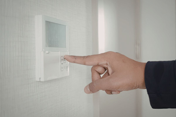 A woman turning on her split-system air conditioning system inside her home in Western Australia.