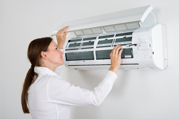 Women checking inside aircon unit for maintenance.