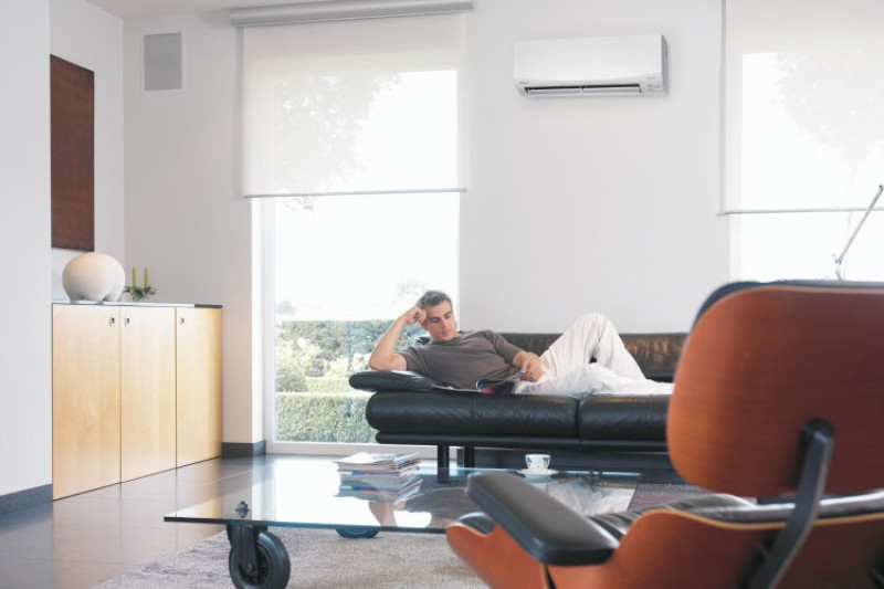 Man sitting on couch with split system air conditioning.